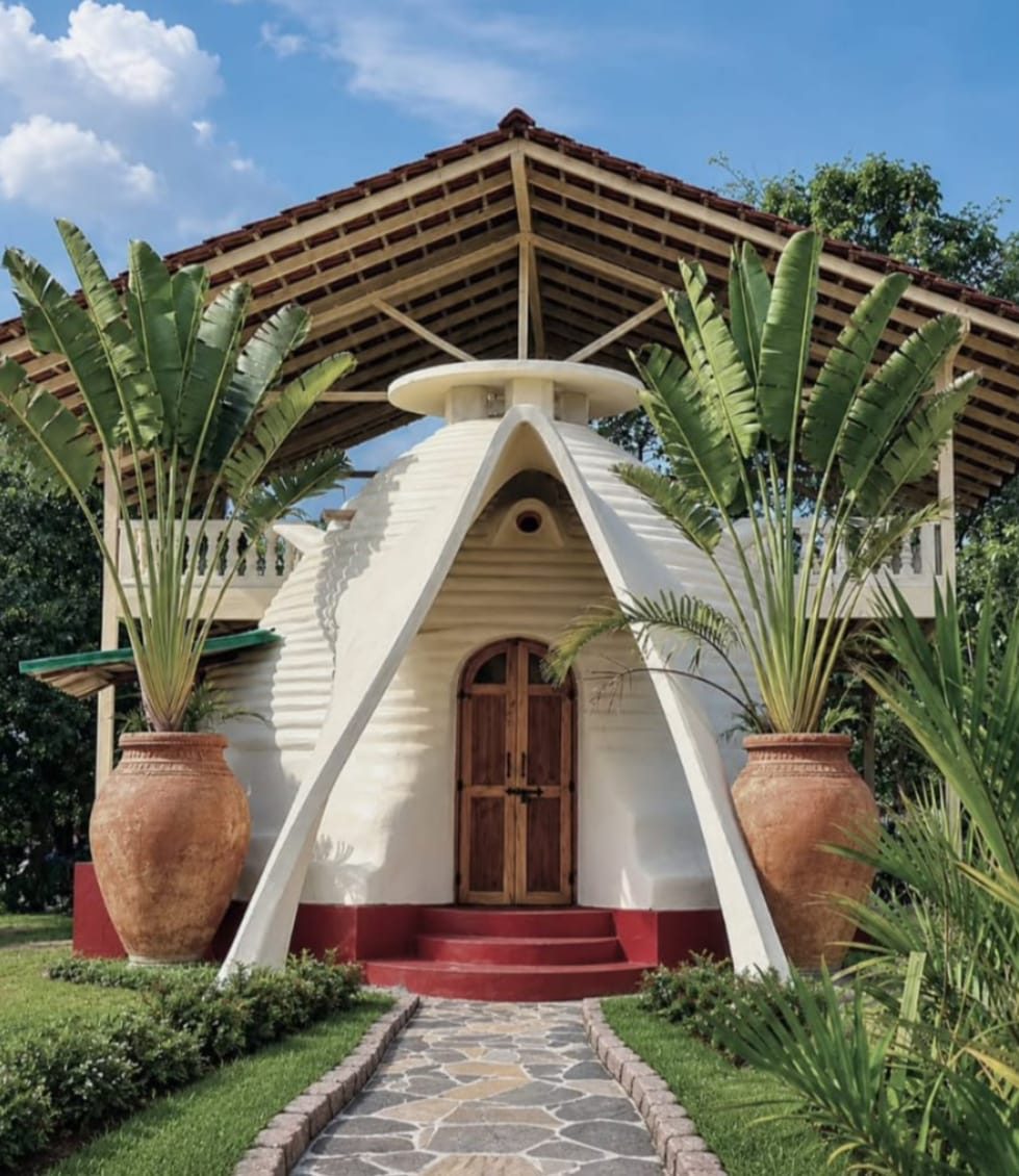 A dome-shaped mud house design reference, with a wide tiled verandah roof
